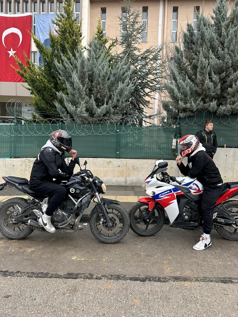 Helmeted riders on two parked motorcycles