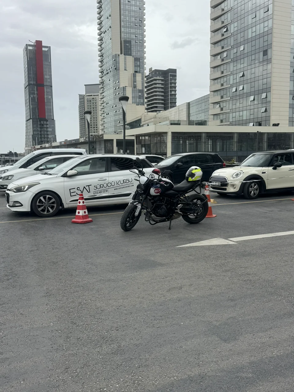 A motorcycle parked between cones with a helmet on the seat