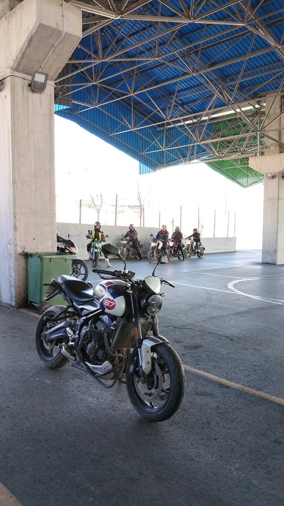 A motorcycle in a covered training area with helmeted riders behind it
